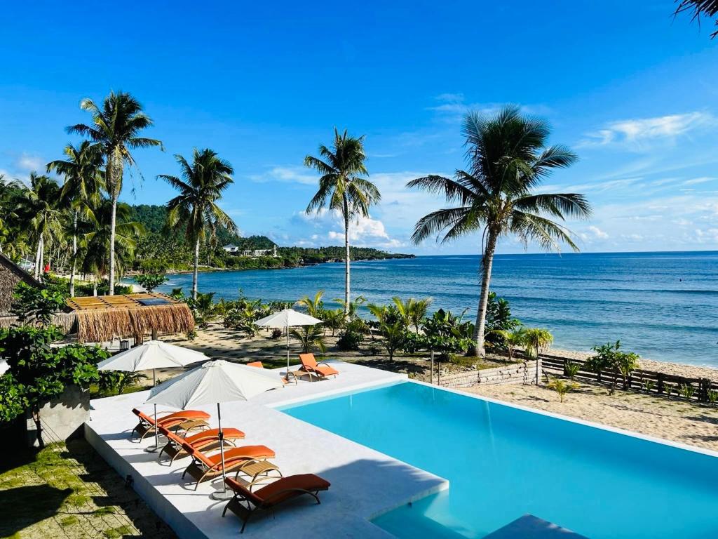 una piscina accanto alla spiaggia con palme di Yapak Beach Villas a San Isidro