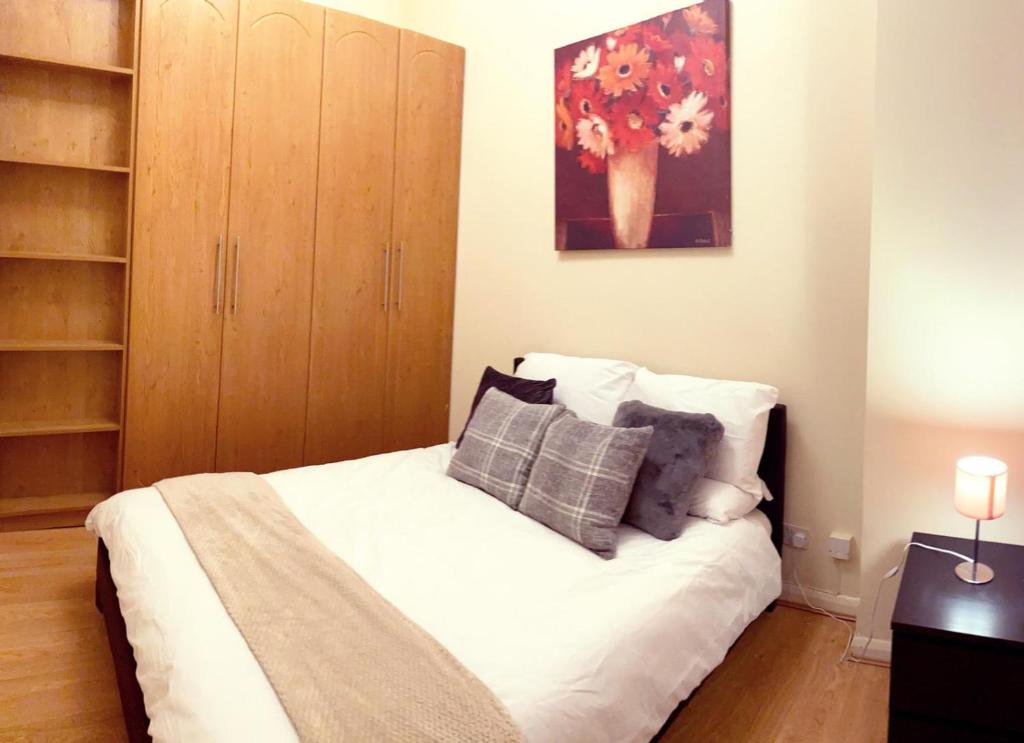 a bedroom with a white bed and a cabinet at UK Chaps Retreat: Balcony Apartment in London