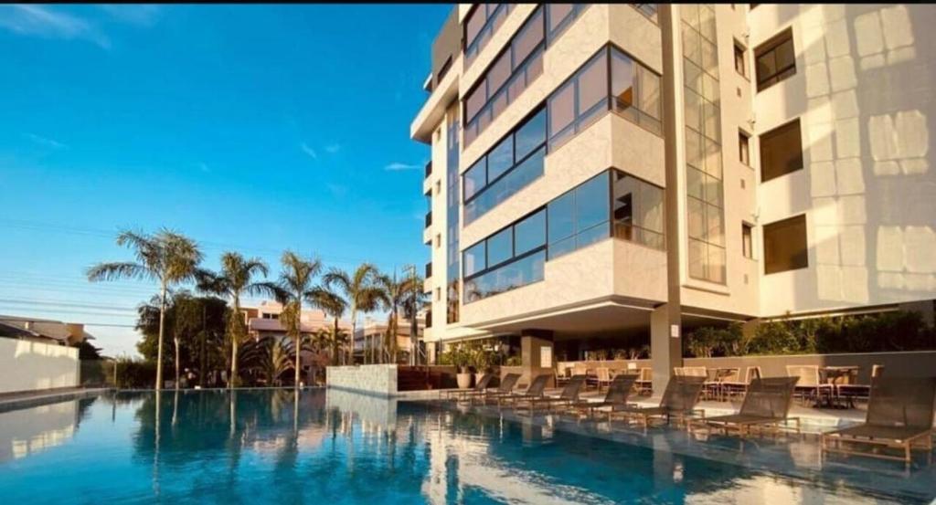 a hotel with a swimming pool in front of a building at Cobertura Palmas in Governador Celso Ramos