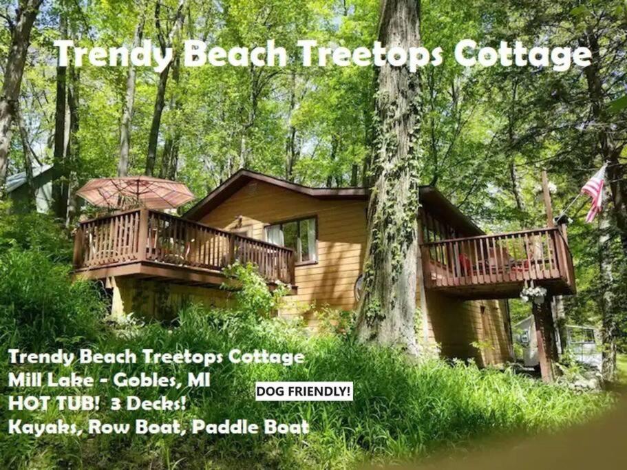 eine Hütte im Wald mit zwei Decks in der Unterkunft Treetop Cottage-Dog Friendly No Fees, Mill Lake, Hot Tub, Kayak, Paddle Boat, Row Boat, Firepit in Gobles