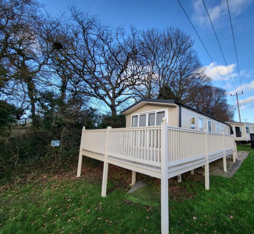 a white house with a white fence in the grass at Beautiful 8 Berth Caravan At Valley Farm Holiday Park, Essex Ref 46362v in Great Clacton