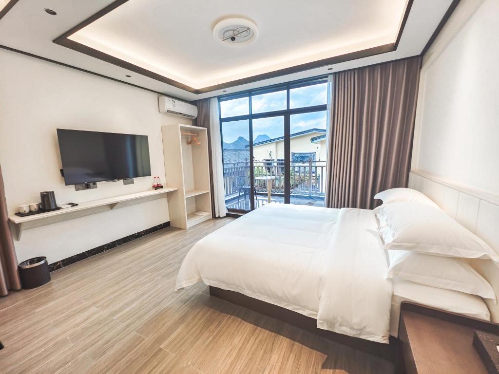 桂林市にあるGuilin Meishe Homestayのベッドとテレビ付きのホテルルーム