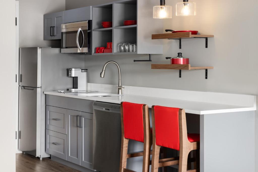 a kitchen with a sink and red chairs at Hawthorn Extended Stay by Wyndham Williston Burlington in Williston