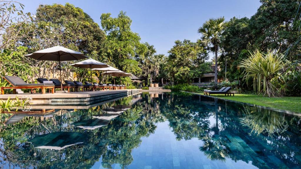 a swimming pool with chairs and umbrellas in a yard at Sala Lodges in Siem Reap