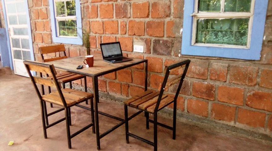 a wooden table with a laptop computer on it next to a brick wall at Kimashuku permaculture garden in Weru Weru