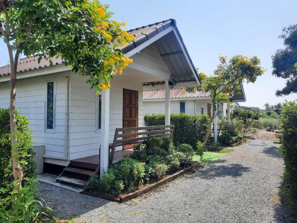 a small white house with a porch and a bench at Homlomchomsuan หอมลมชมสวน in Ban Mai