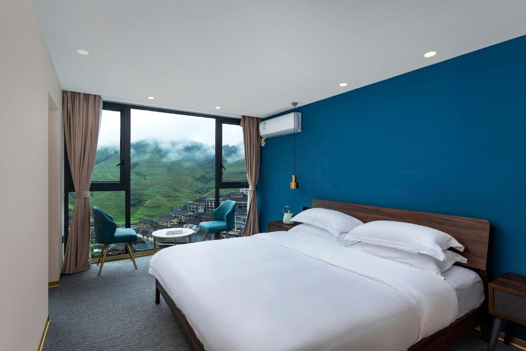 a bedroom with a large bed with a blue wall at Lost In Beauty Guest House 龙脊梯田野望民宿 in Longsheng