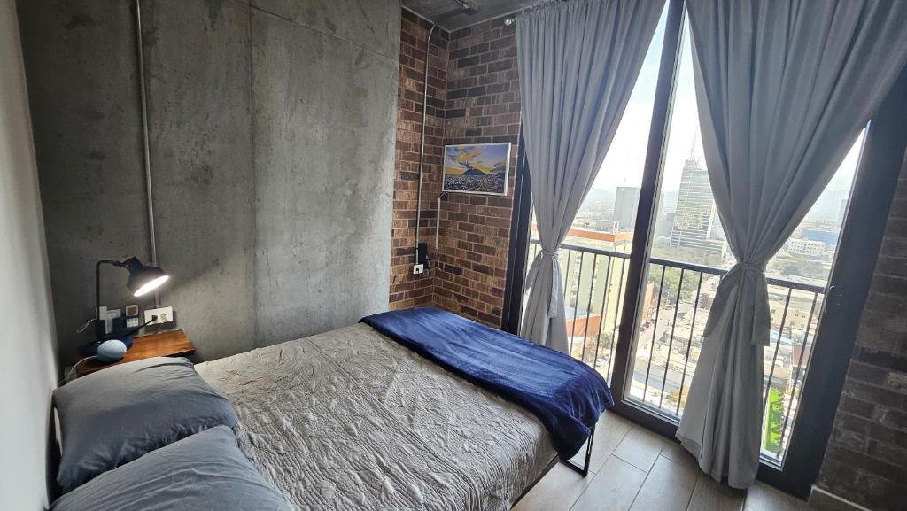 a bedroom with two beds and a large window at Depto en el centro de Monterrey. in Monterrey
