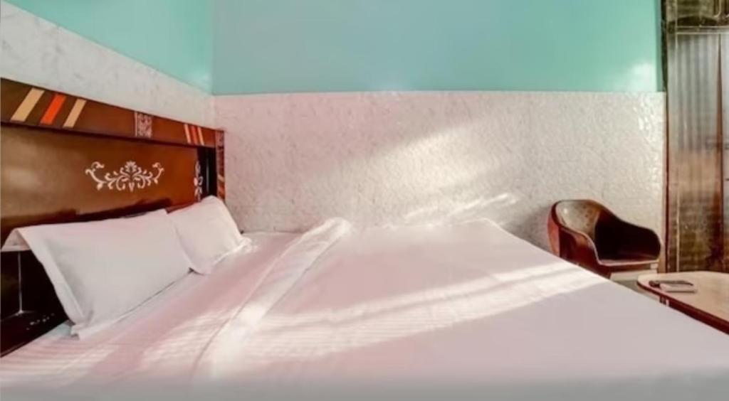 a bedroom with a large white bed and a chair at Tarun guest house in Palwal