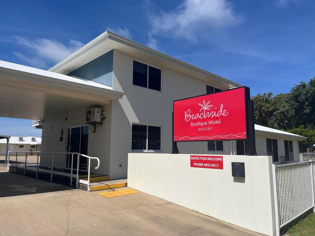 a building with a red sign in front of it at Beachside Boutique Motel Mackay in Mackay