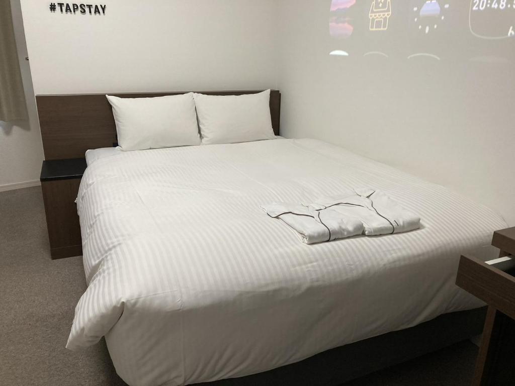 ein Bett mit weißer Bettwäsche und weißen Schuhen darauf in der Unterkunft TAPSTAY HOTEL - Vacation STAY 35240v in Saga