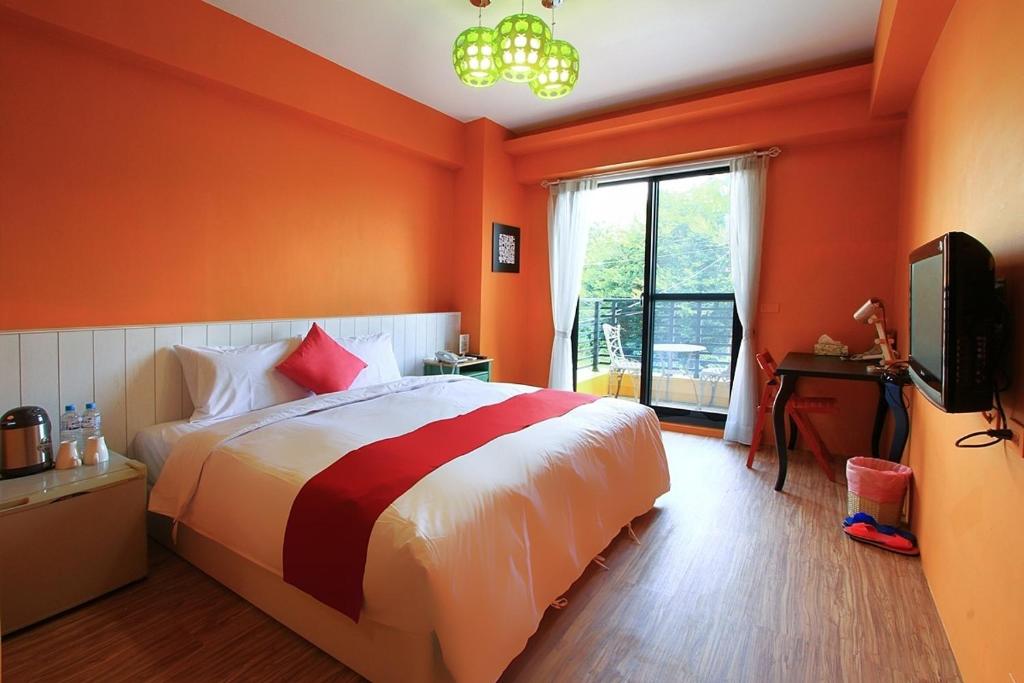 a bedroom with orange walls and a bed and a television at Yu Sen House in Kenting