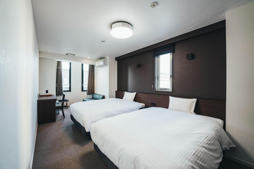 佐賀市にあるTAPSTAY HOTEL - Vacation STAY 35239vのベッド2台とデスクが備わるホテルルームです。