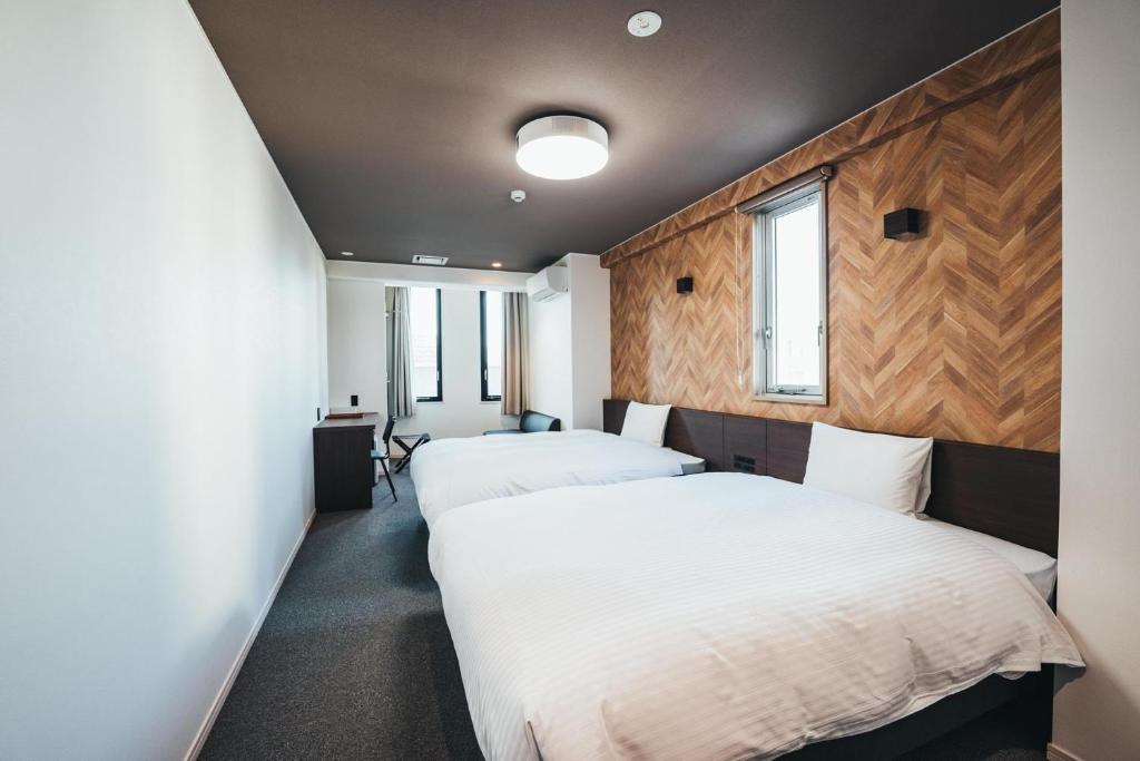 TAPSTAY HOTEL - Vacation STAY 35237v في ساغا: سريرين في غرفة بجدران خشبية ونوافذ