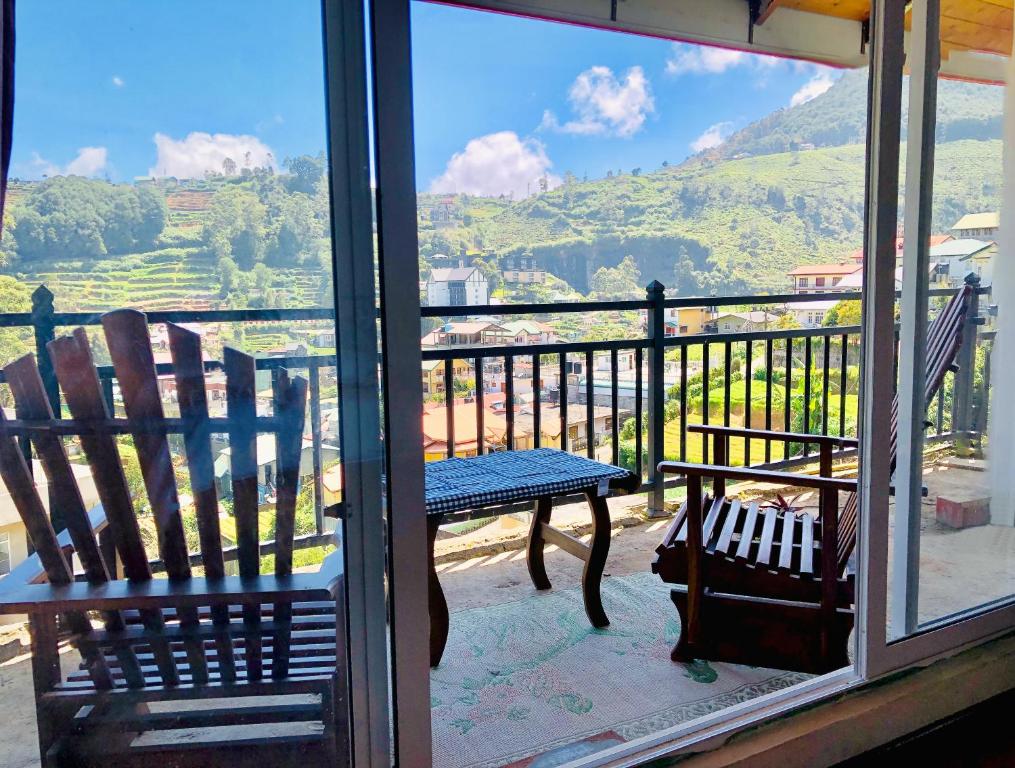 Duas cadeiras e um banco numa varanda com vista em Star Holiday Home em Nuwara Eliya