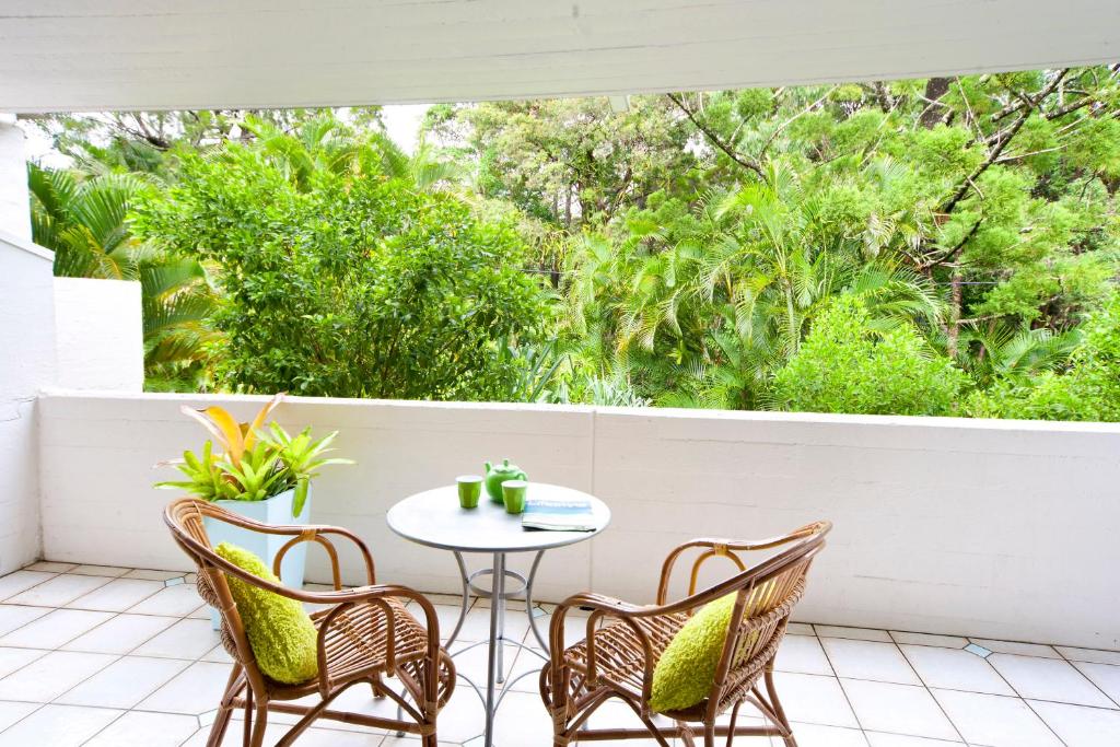 un patio con mesa, sillas y árboles en Tea Trees Apartment 4, Little Cove, en Noosa Heads