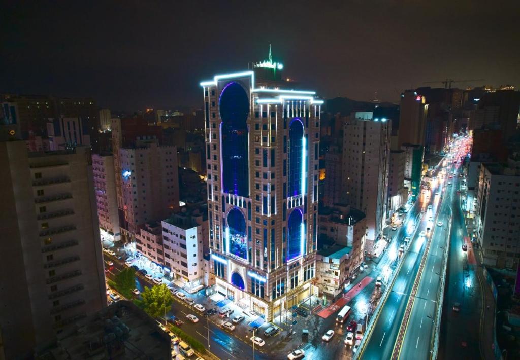 un grand bâtiment avec des lumières bleues sur une ville la nuit dans l'établissement Selat Al Bait Hotel, à La Mecque