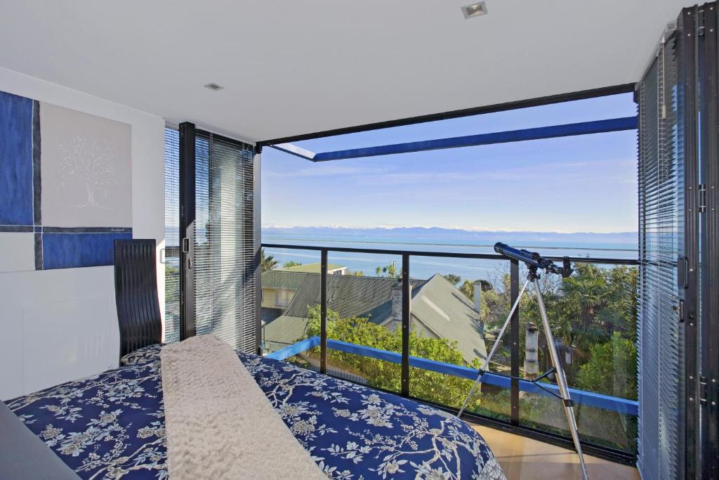 um quarto com uma cama e uma grande janela em Coastal Escape em Nelson