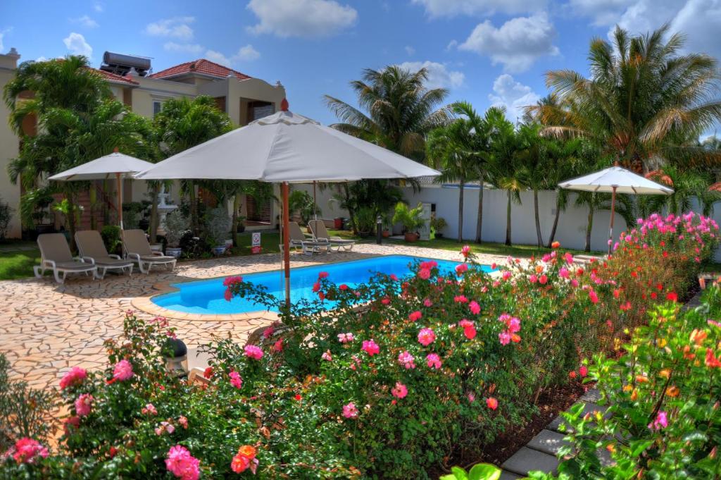 a swimming pool with an umbrella and flowers at La Pointe Villas in Pointe aux Cannoniers