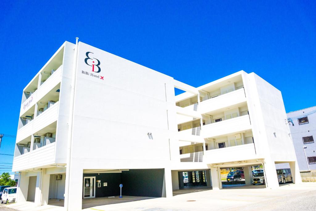 Un bâtiment blanc avec un panneau. dans l'établissement BiBi Hotel 宮古空港前, à Île Miyako