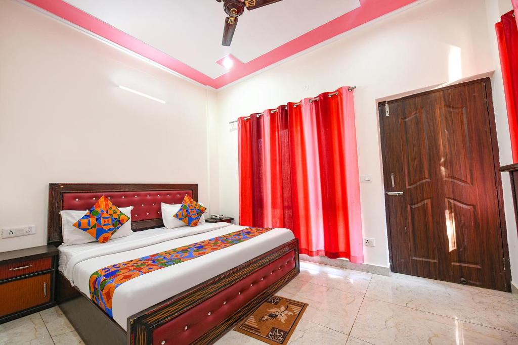 a bedroom with a bed with red curtains and a door at FabHotel Kempty Lake Resort in Mussoorie
