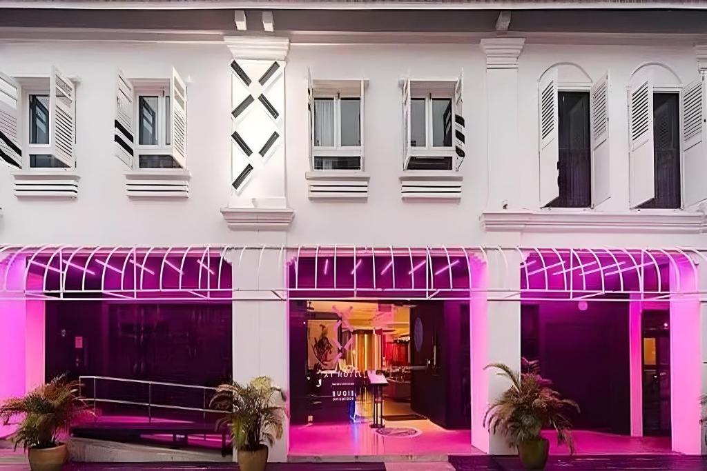 a white building with pink lighting in front of it at Hi Hotel Bugis in Singapore