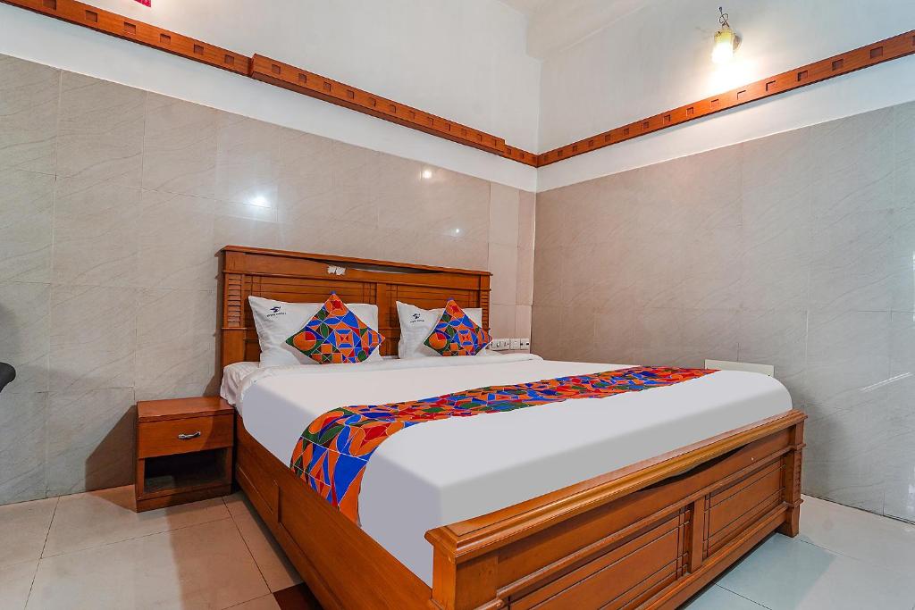 a bedroom with a large bed with a wooden headboard at FabHotel Skyry I in Coimbatore