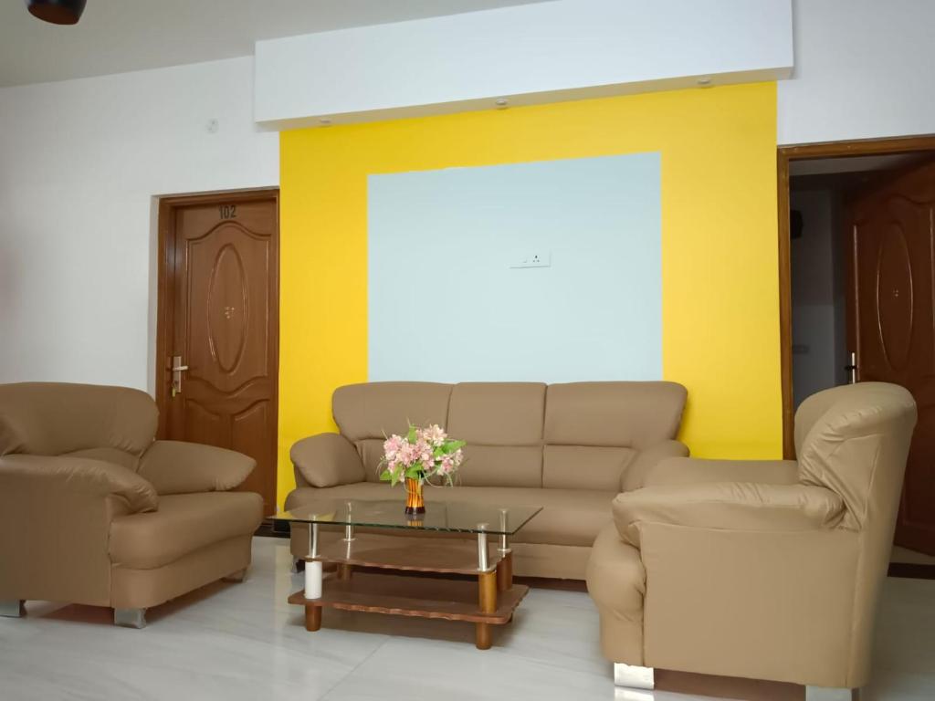 a living room with two chairs and a couch and a table at SAVIS home stay in Ooty