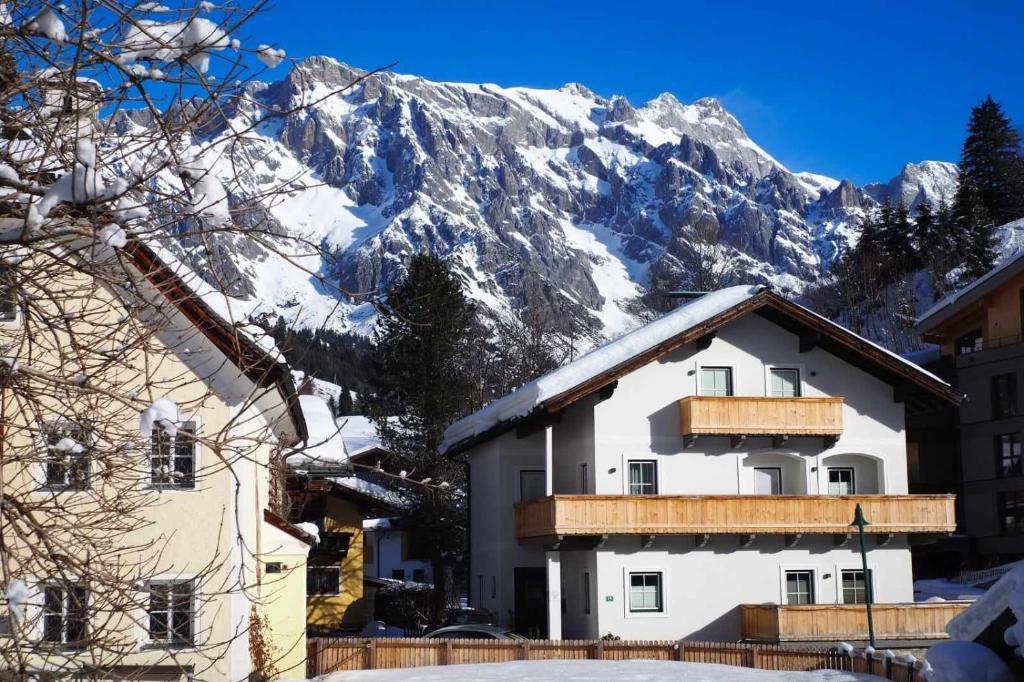 un edificio con una montaña cubierta de nieve en el fondo en Leni`s Mountain Appartements, en Dienten am Hochkönig