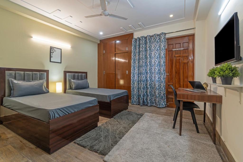 a bedroom with two beds and a desk and a television at Wandr Regor - Sector 38, Near Medicity Medanta in Gurgaon