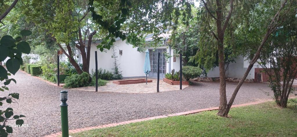 una casa blanca con un banco en un patio en DRIFTWOOD BOUTIQUE BED AND BREAKFAST, en Lobatse