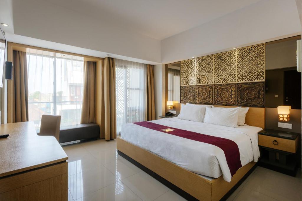 a hotel room with a large bed and a desk at Horison Ultima Seminyak Bali - CHSE Certified in Seminyak