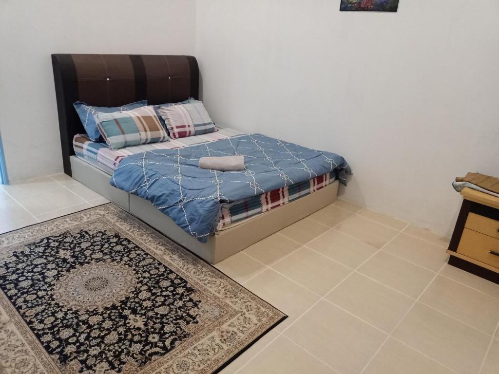 a bedroom with a bed with a blue comforter and a rug at D'RinduVillage Homestay in Marang