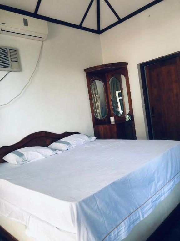 a bedroom with a white bed with a wooden headboard at Sarojeni Apartments and Rooms in Negombo