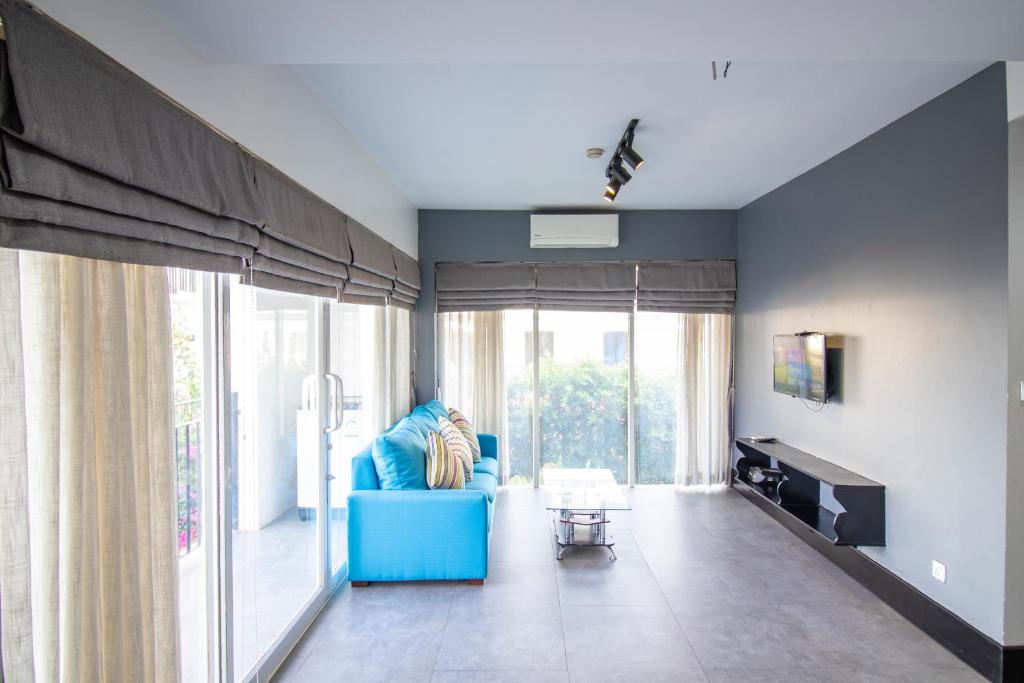 a living room with a blue couch and large windows at 1 BR Serviced Apt In The Heart of Siem Reap in Siem Reap