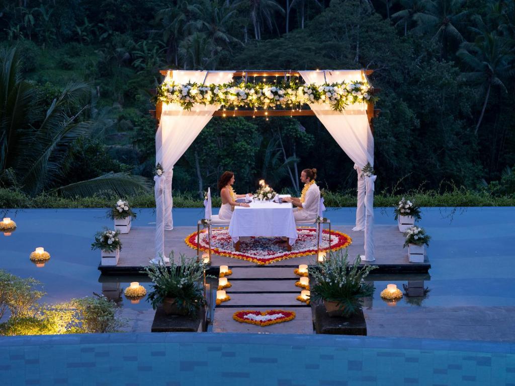 two women sitting at a table under an arch with lights at Jannata Resort and Spa in Ubud