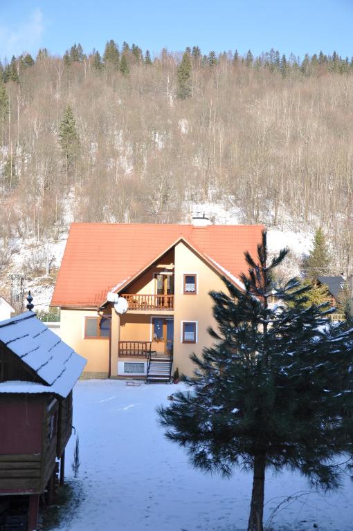 a house with an orange roof in the snow at Apartmán pod Veľkou Račou in Čadca