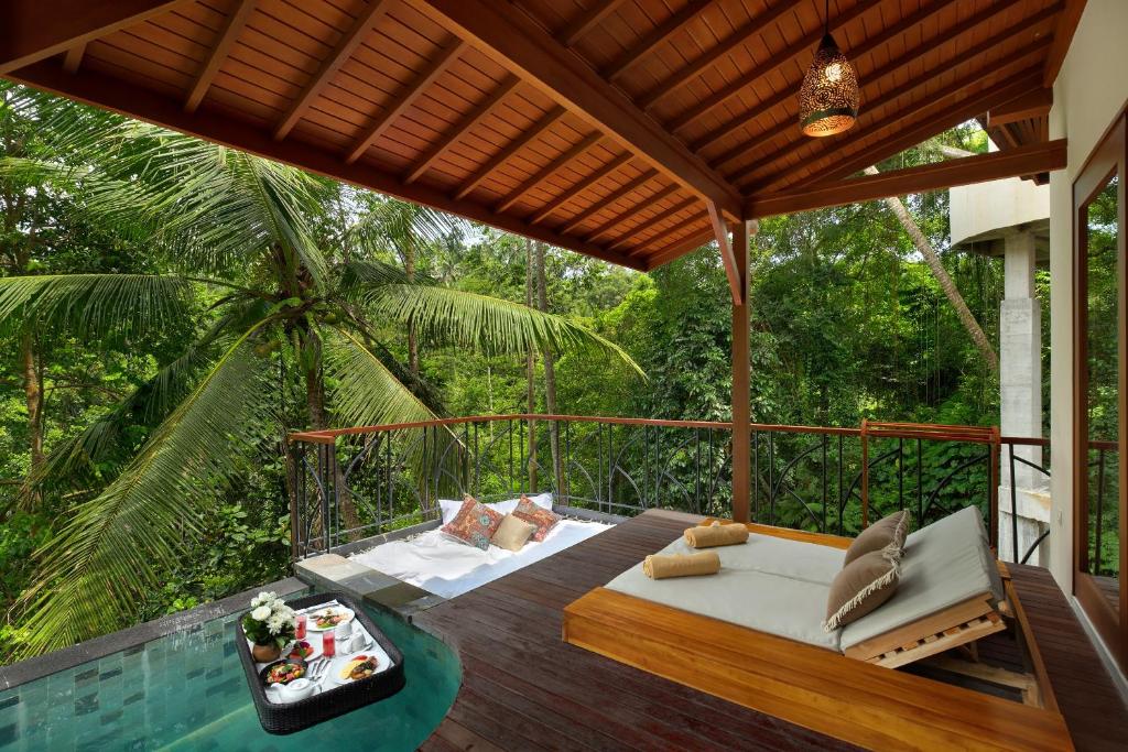 eine Terrasse mit einem Bett und einem Tisch auf einer Terrasse in der Unterkunft Jannata Resort and Spa in Ubud