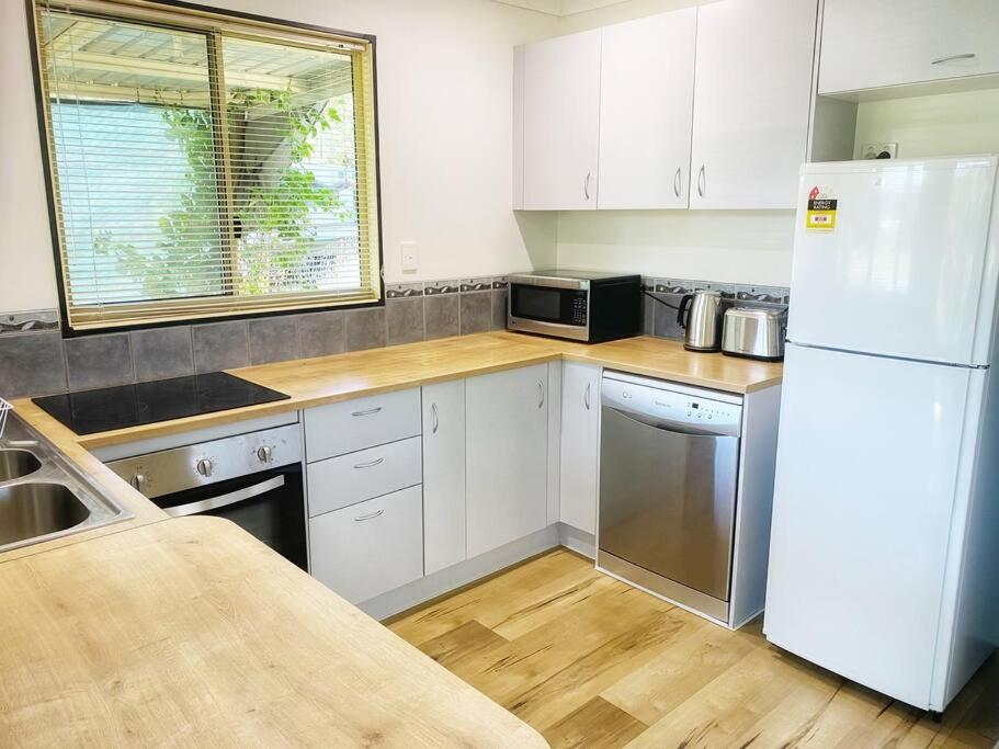a kitchen with white cabinets and a white refrigerator at Cosy house among the trees in Pemberton