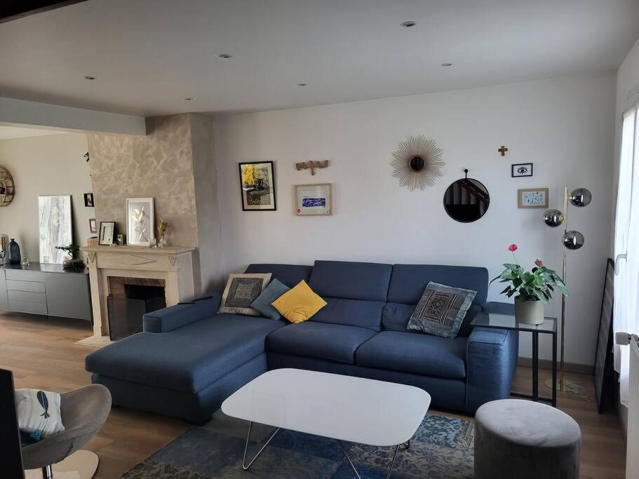 een woonkamer met een blauwe bank en een open haard bij Maison indépendante avec jardin, ville JO 2024 in Vaires-sur-Marne