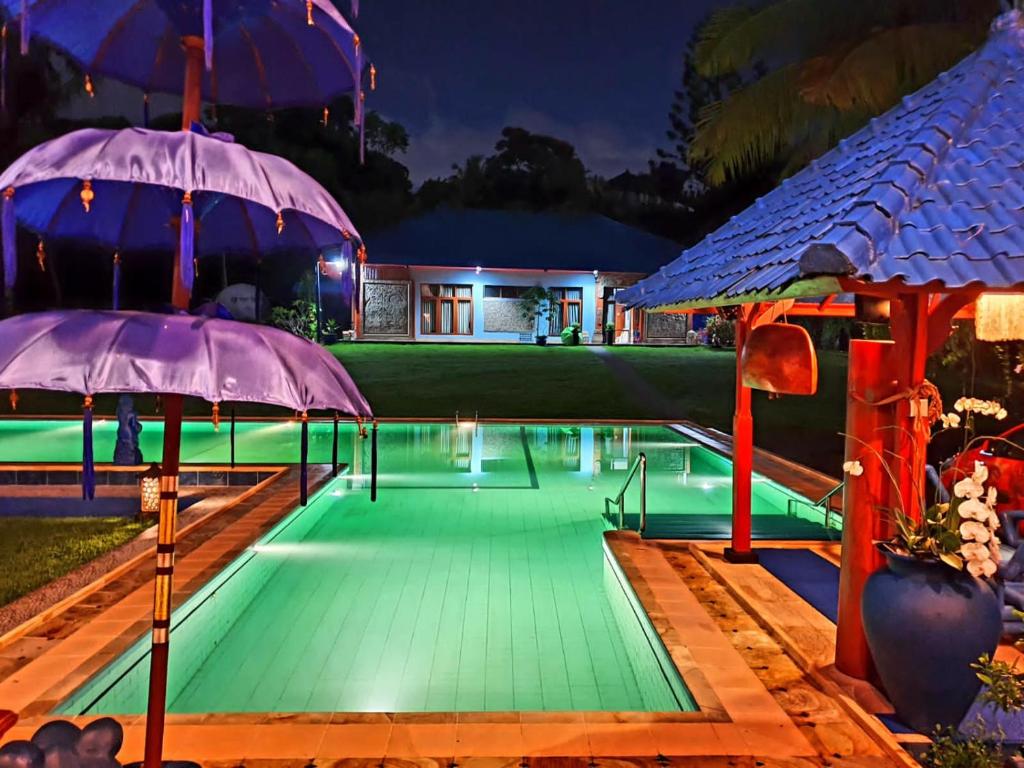 a pool with two umbrellas next to a house at Villa Biyu Siyu in Ubud