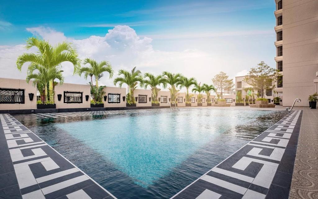 uma piscina com palmeiras e edifícios em 秘狗公寓City garden em Pattaya Sul