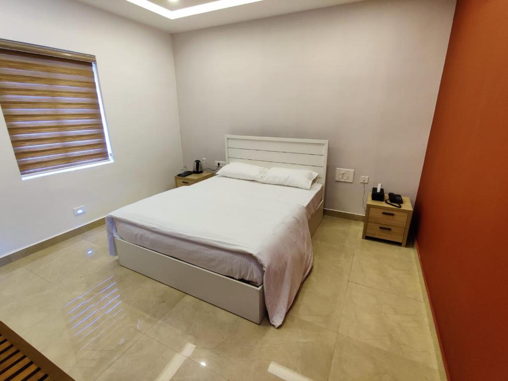 1 dormitorio con cama blanca y ventana en LGR Club House en Poringalkuthu