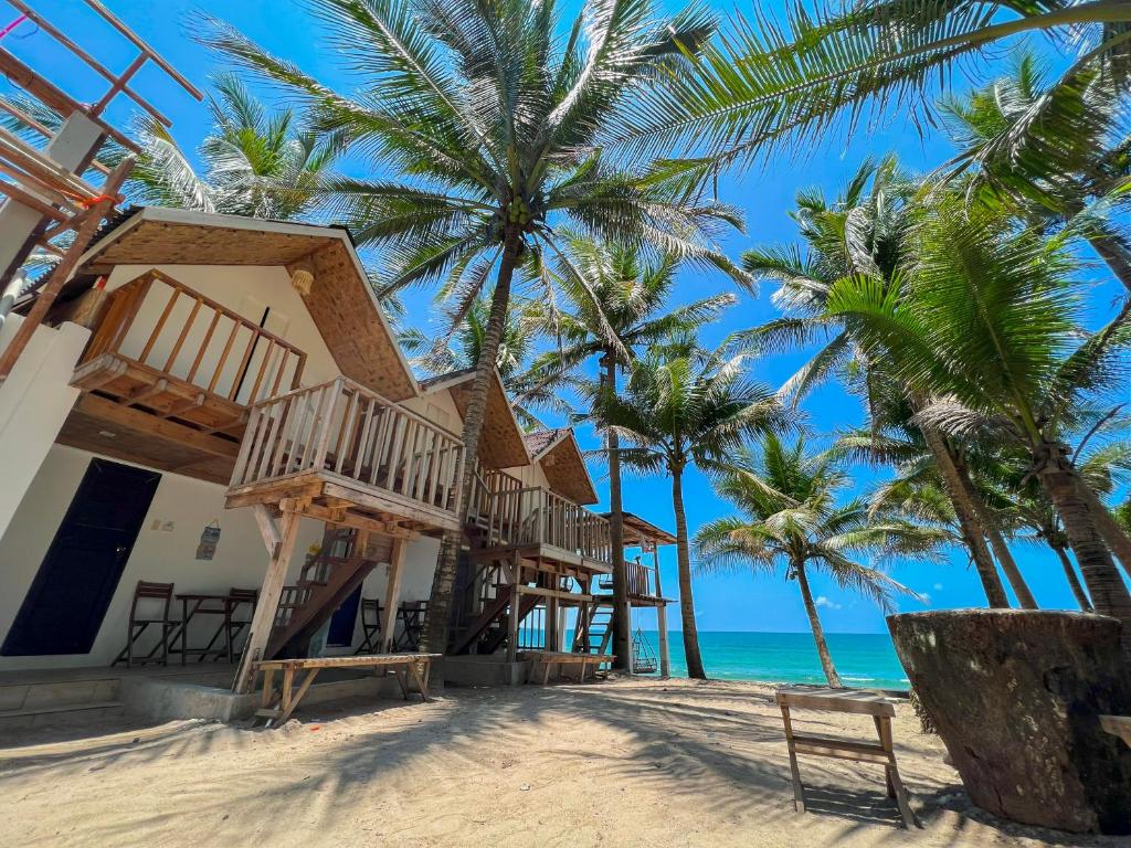 dom na plaży z palmami i oceanem w obiekcie Pipa de Playa Resort Café w mieście Gubat