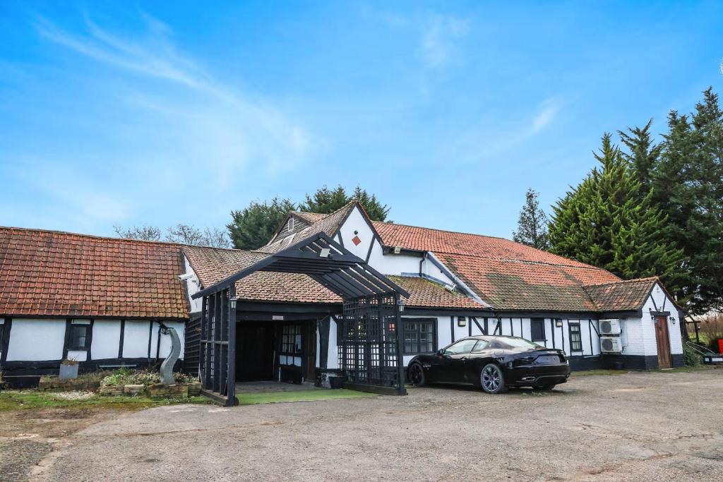 ein Haus mit einem davor geparkt in der Unterkunft OYO Tudor Oaks Lodge Stevenage North in Astwick