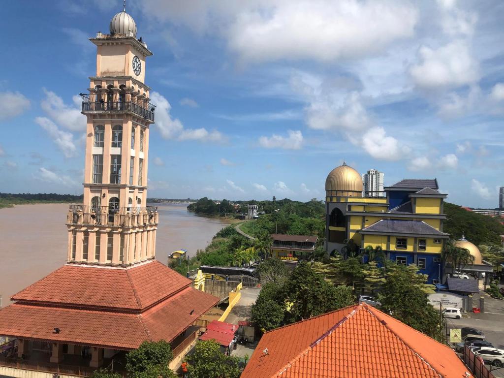 a clock tower and a building with a river at Ridel Sunset Hotel in Kota Bharu