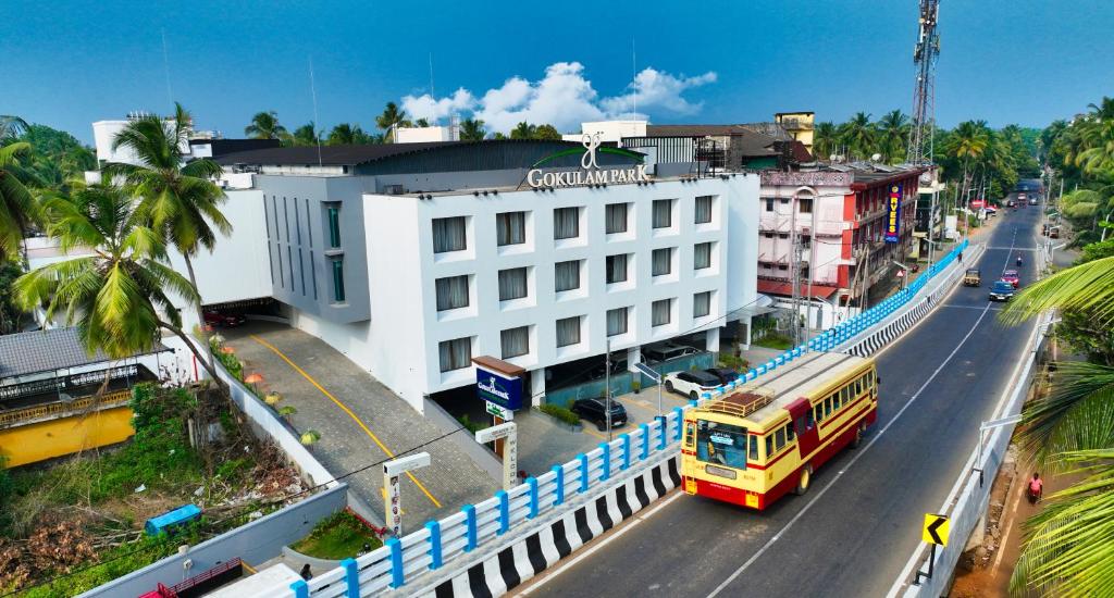 un bus jaune circulant dans une rue à côté d'un bâtiment dans l'établissement Gokulam Park Guruvayur, à Guruvāyūr