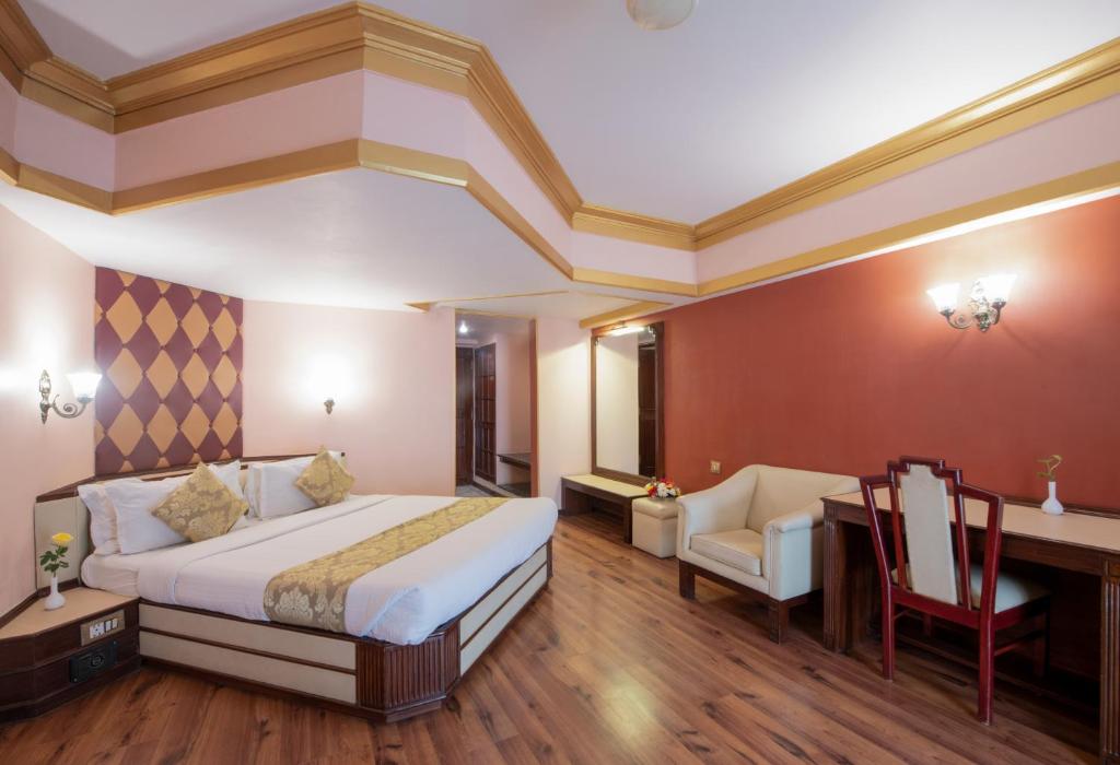 a hotel room with a bed and a desk and chair at Nahar Heritage Hotel in Bengaluru