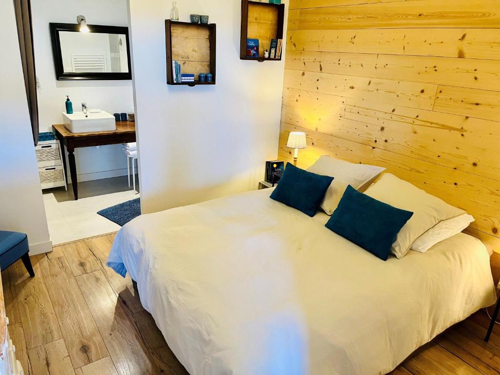 a bedroom with a white bed with a wooden wall at Gîtes du Fort in Collonges