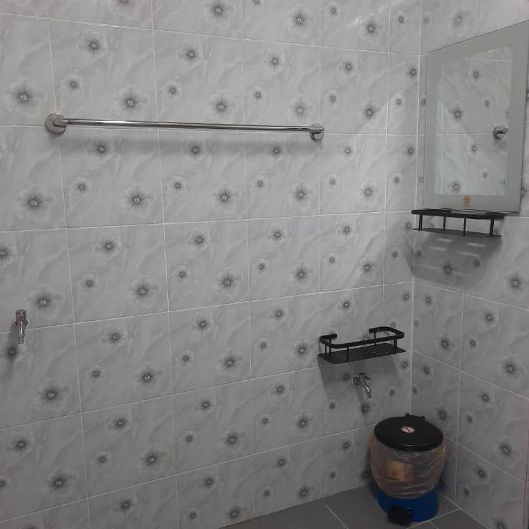 a white tiled bathroom with a toilet and a mirror at Hidden Homestay in Marang